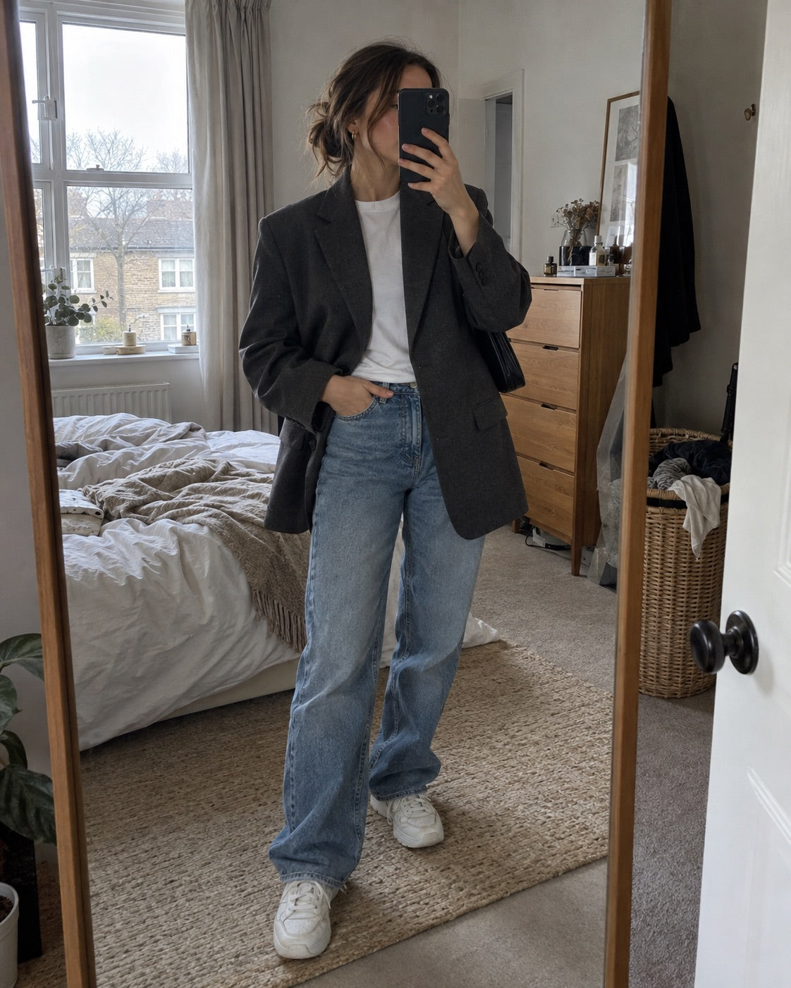 Woman wearing a charcoal blazer and jeans in a bedroom mirror selfie