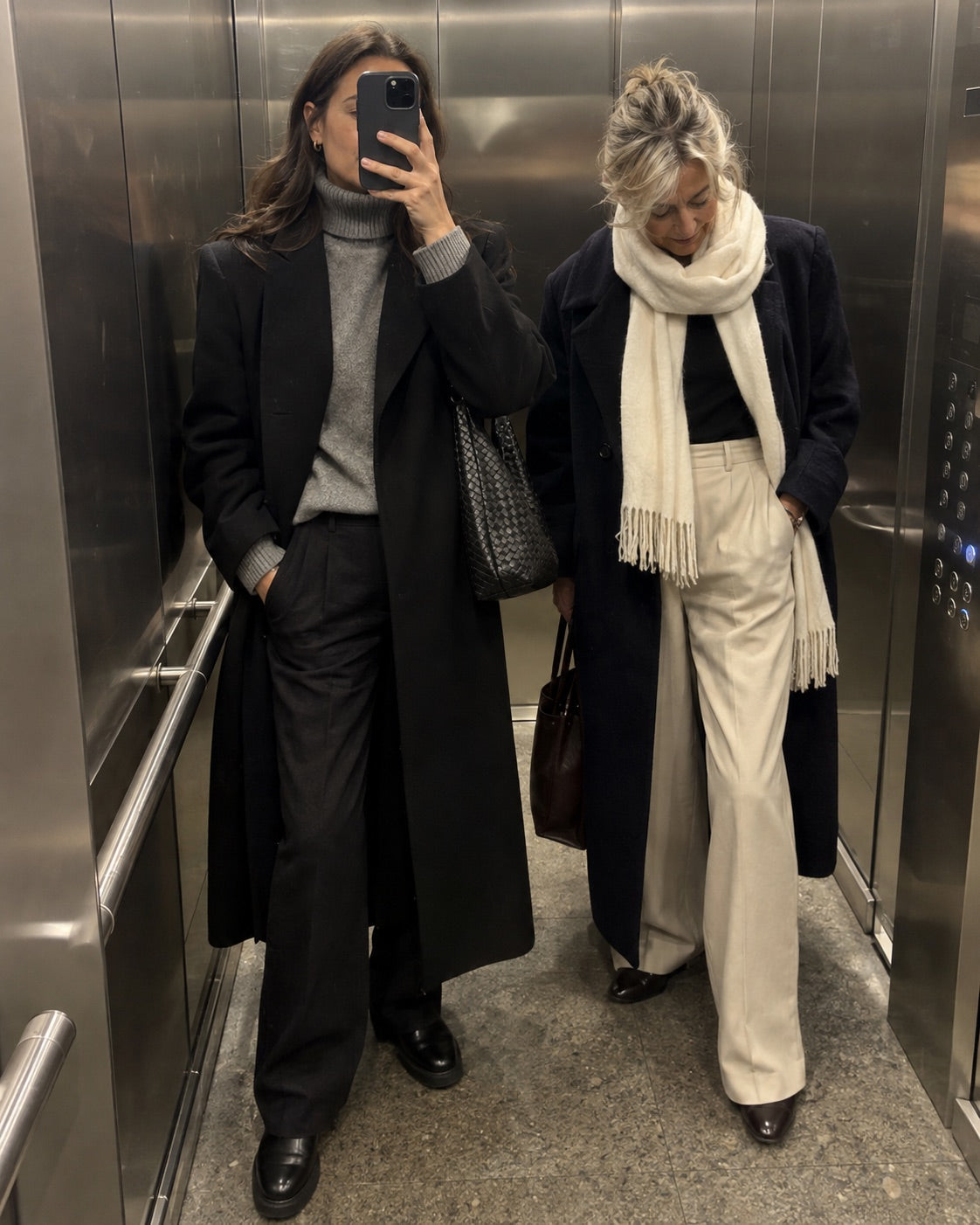 Two women in timeless coats taking a lift mirror selfie